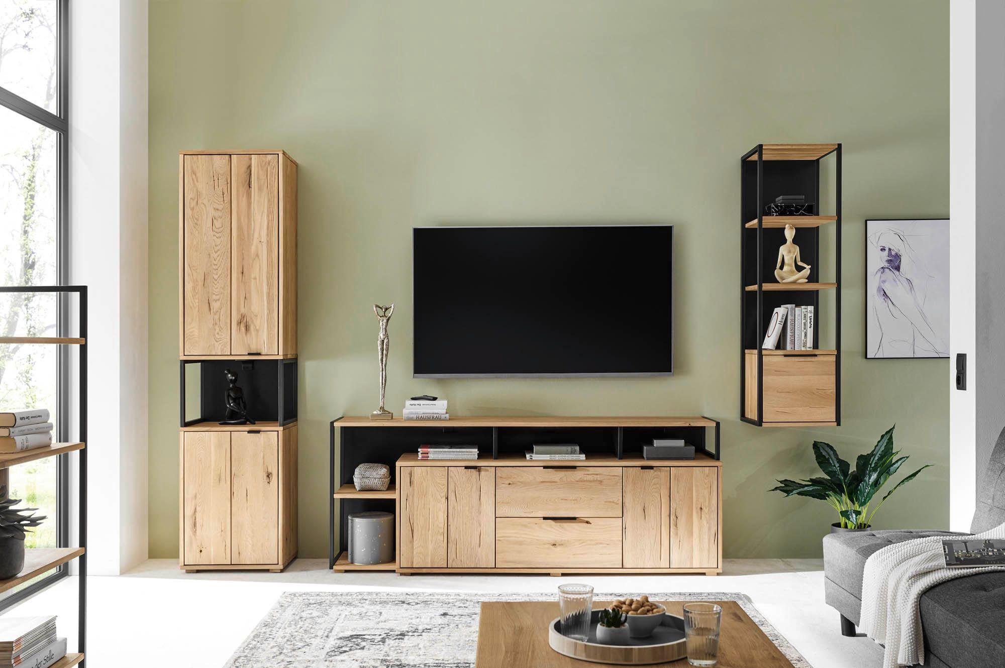 Moderne Wohnwand Candia mit TV-Board, hoher Vitrine und Hängeregal in natürlicher Holzoptik, kombiniert mit schwarzem Metallrahmen vor grüner Wand