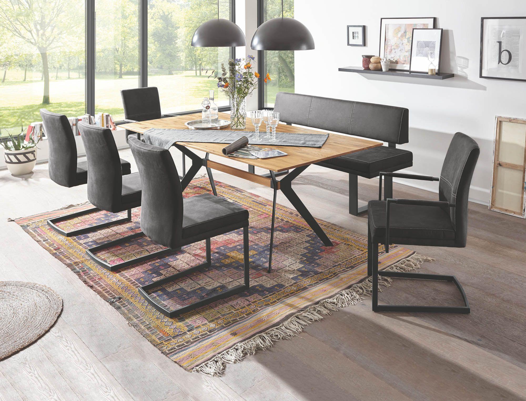 Caja Essgruppe mit Eichenholztisch auf schwarzem X-Gestell, anthrazitfarbenen Freischwingern und Sitzbank, bunter Kelim-Teppich im modernen Essbereich