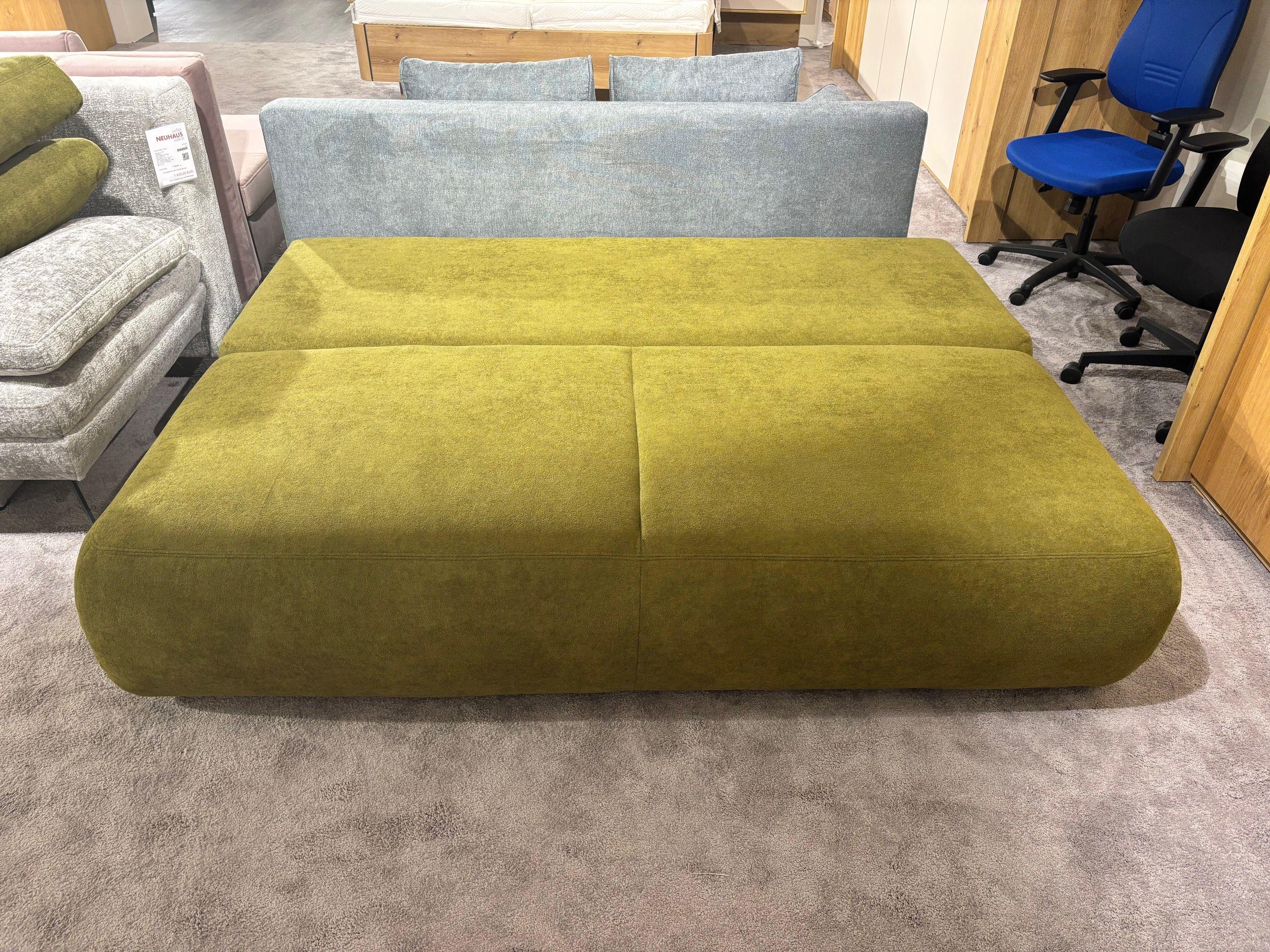 Ausgeklapptes grünes Schlafsofa mit durchgehender Liegefläche, frontal fotografiert.