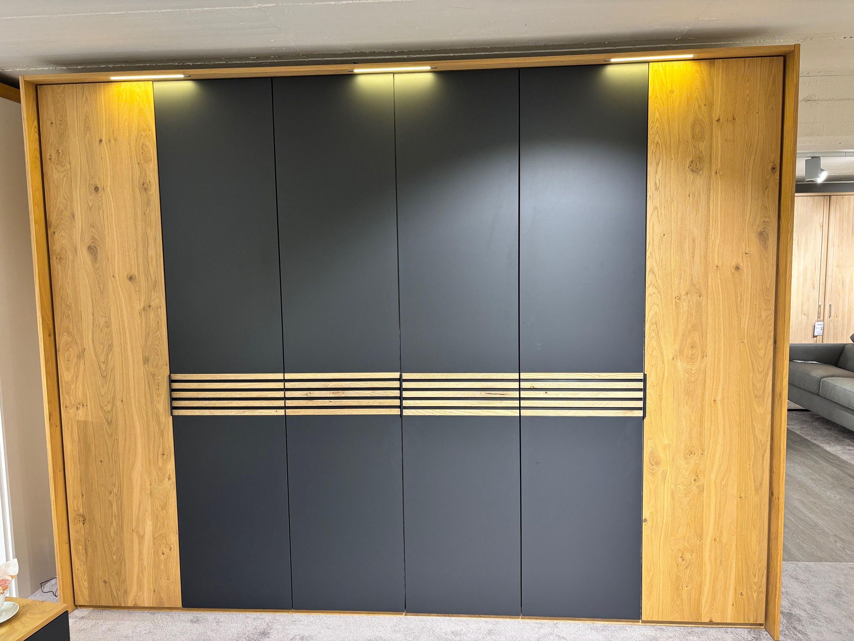 Großer Drehtürenschrank in Anthrazit matt mit Eiche-Seitenteilen, Holzlamellen-Akzent und integrierter LED-Beleuchtung.