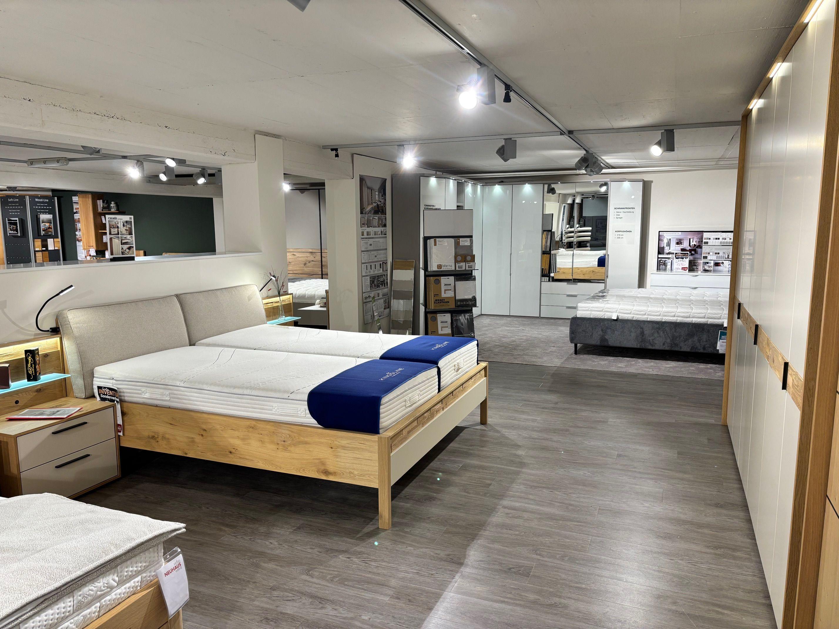 Schlafzimmer-Ausstellung mit Eiche-Doppelbett, Kingsline-Matratzen, Nachttischen und Kleiderschränken im Hintergrund.